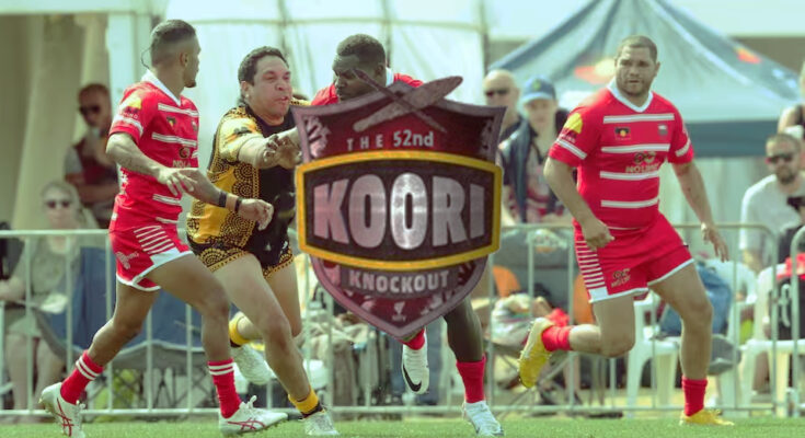 four footballs chasing a ball with the 52nd Koori Knockout shield in the middle of the image