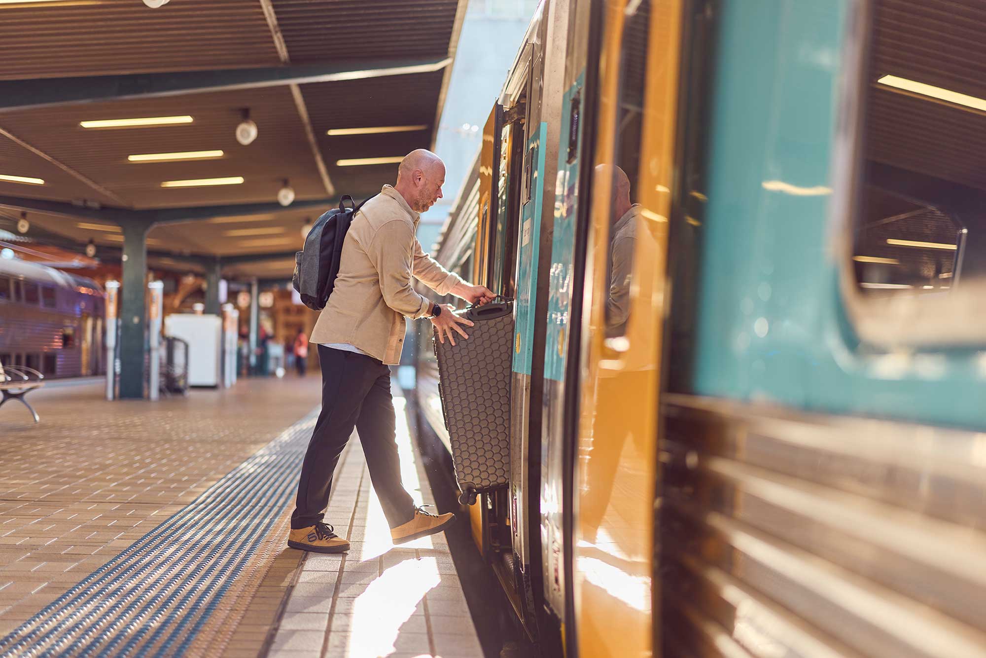 Man bringing luggage onto a regional train.