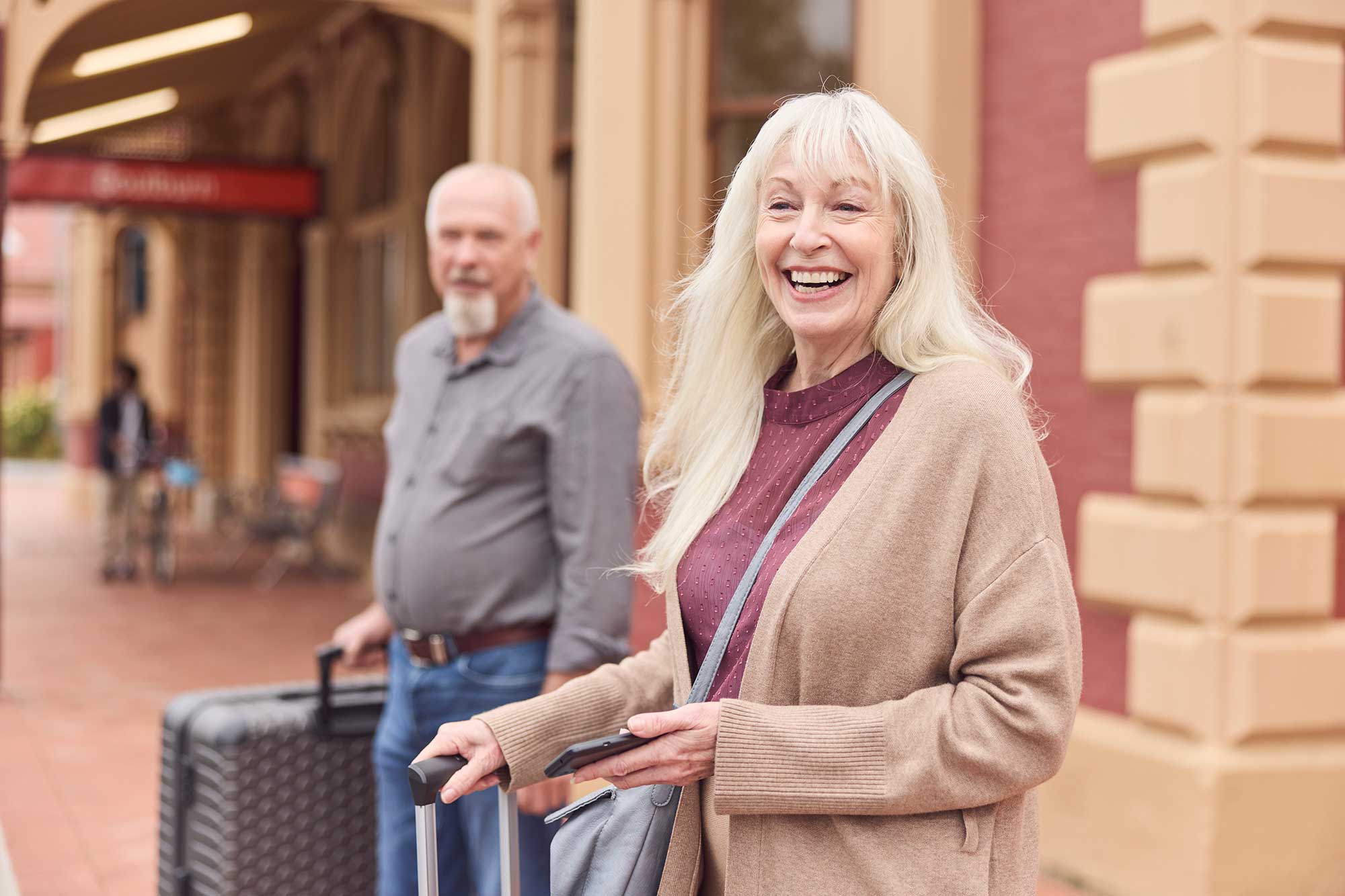 Passengers waiting at the station with luggage.