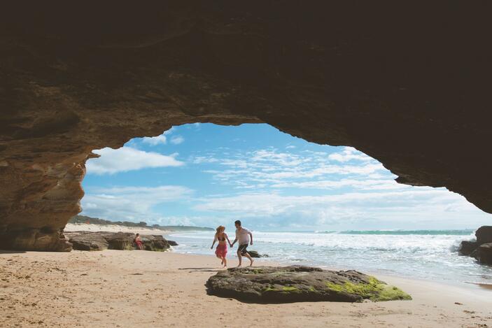 A couple inside a cave on a beach