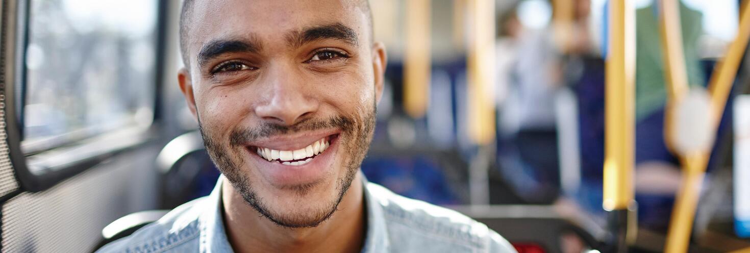 young adult man on bus close up face smiling blue shirt