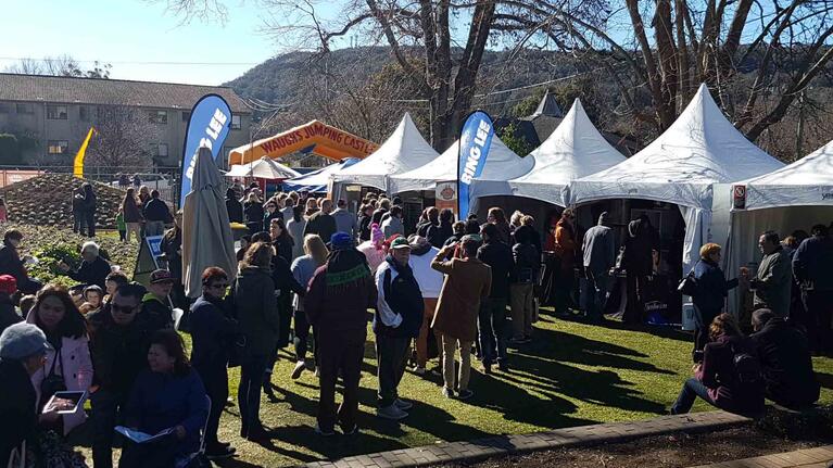 Groups of people at PieFest, eating pies outdoors at the festival