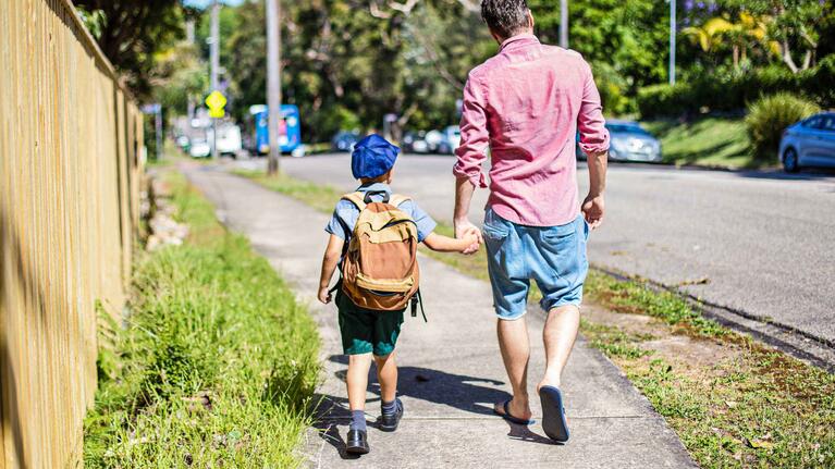 School child and father walking on a path