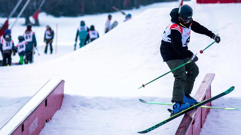 Skiier skis down rails