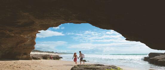 A couple inside a cave on a beach